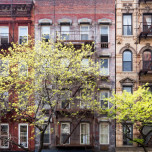 a row of new york city apartments with trees in front.